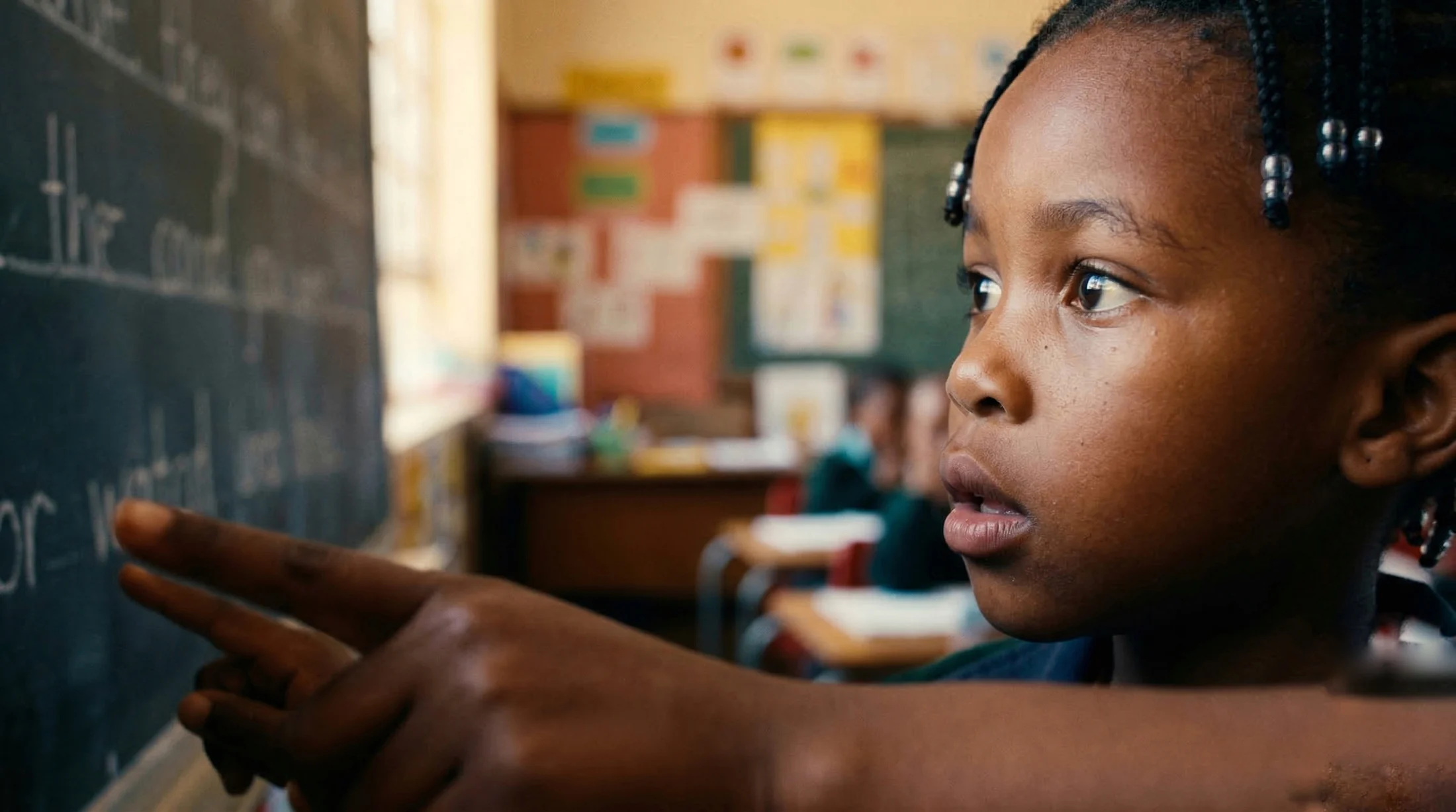 A young student writing on a blackboard, working through a problem by hand